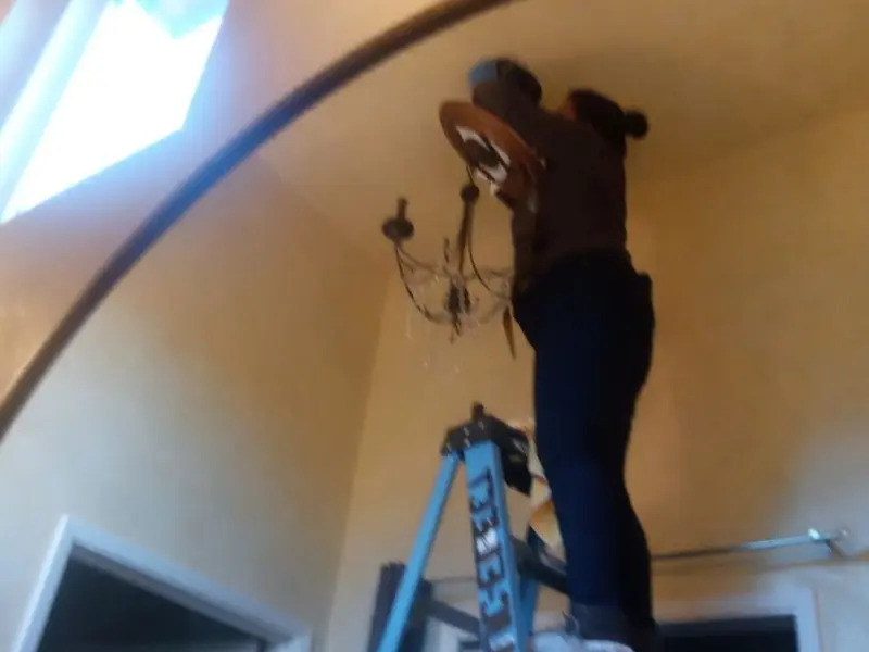 Electrician installing a chandelier in a San Fernando residence